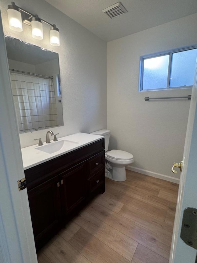 bathroom featuring curtained shower, wood-type flooring, toilet, and vanity