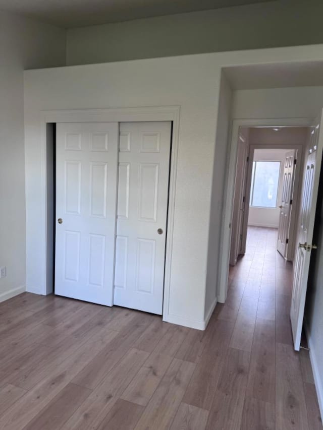 unfurnished bedroom with a closet and light hardwood / wood-style floors