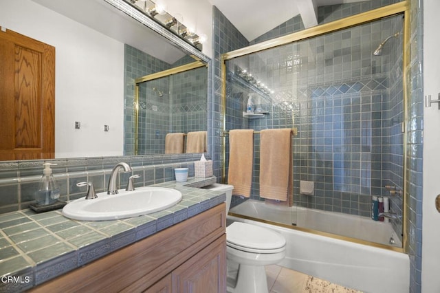 full bathroom with vanity, shower / bath combination with glass door, tile patterned floors, vaulted ceiling, and toilet