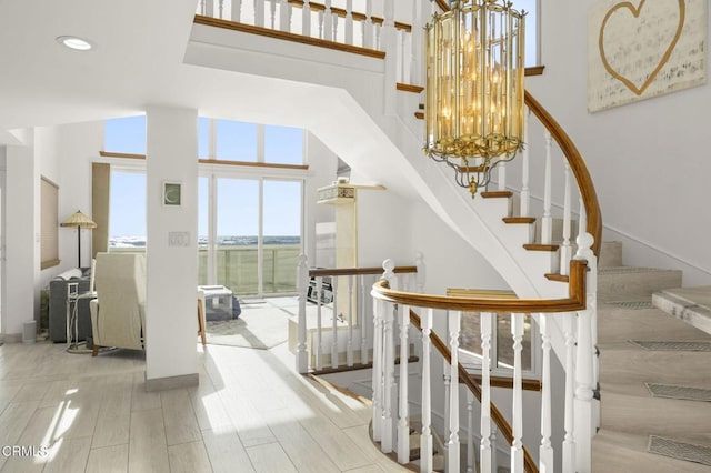 stairs featuring wood-type flooring, a high ceiling, and a notable chandelier