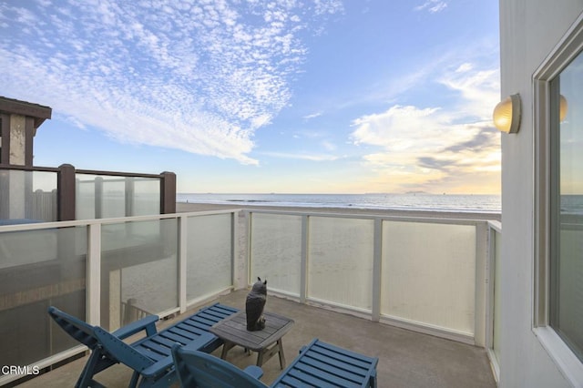 balcony at dusk with a water view and a beach view