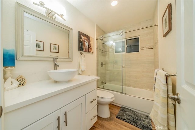 full bathroom with vanity, hardwood / wood-style flooring, toilet, and bath / shower combo with glass door