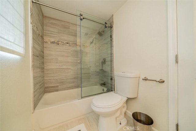 bathroom featuring toilet and bath / shower combo with glass door