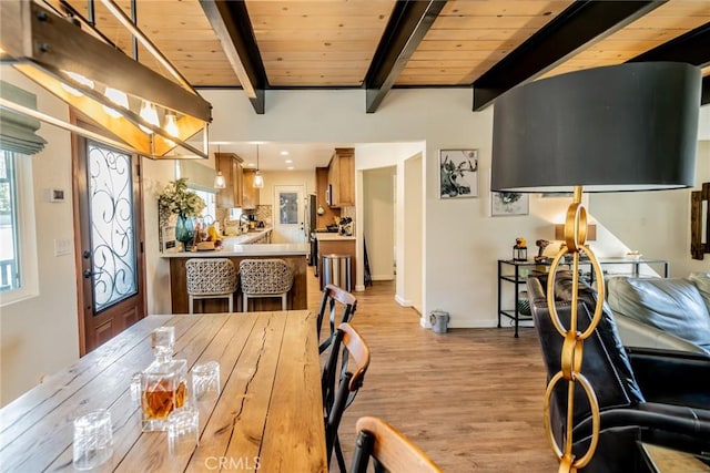 dining space with light hardwood / wood-style flooring, beamed ceiling, and wooden ceiling