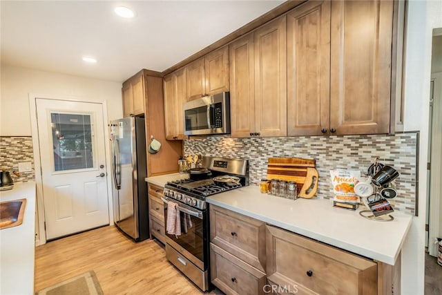 kitchen featuring light wood-type flooring, stainless steel appliances, tasteful backsplash, and sink