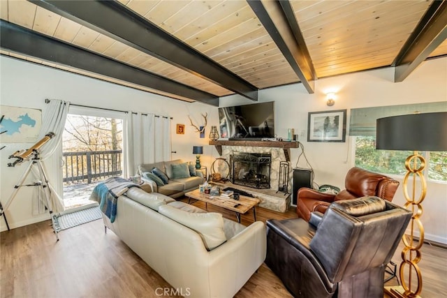 living room with beam ceiling, a stone fireplace, wooden ceiling, and light hardwood / wood-style flooring