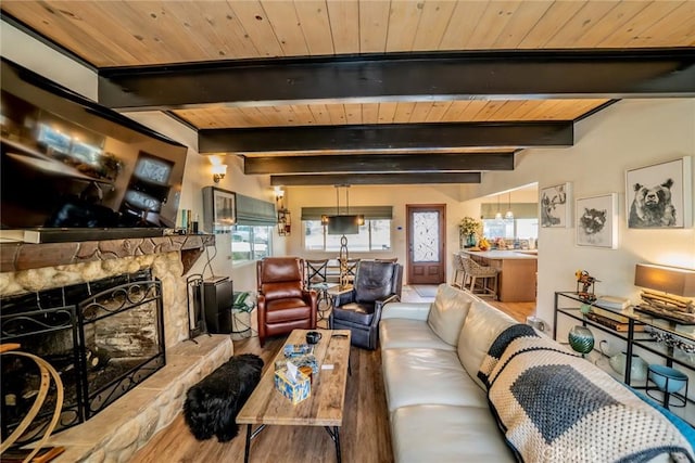 living room featuring beam ceiling, a stone fireplace, hardwood / wood-style floors, and wooden ceiling