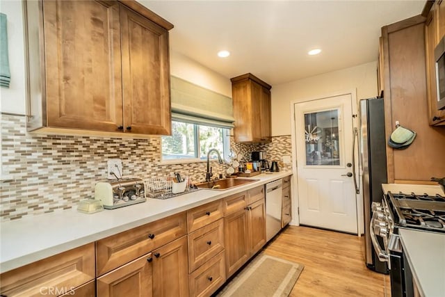 kitchen with decorative backsplash, appliances with stainless steel finishes, light hardwood / wood-style flooring, and sink