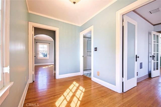 hall with hardwood / wood-style floors, ornamental molding, and french doors