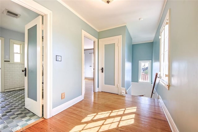 corridor with hardwood / wood-style flooring, plenty of natural light, and ornamental molding