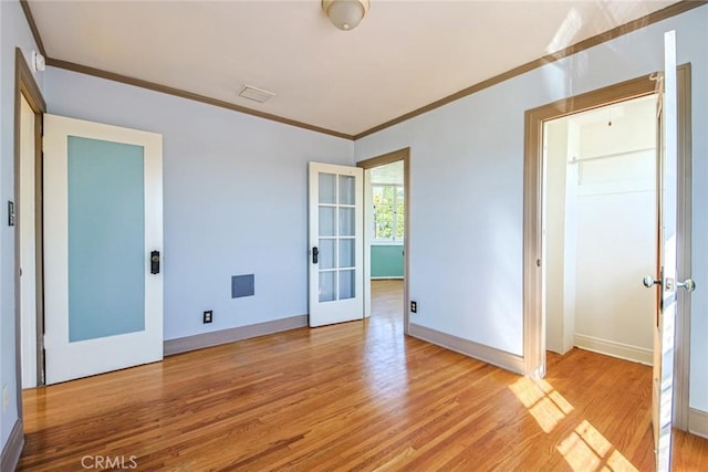 unfurnished room with light wood-type flooring, crown molding, and french doors