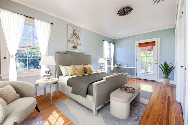 bedroom featuring hardwood / wood-style floors, crown molding, and access to outside