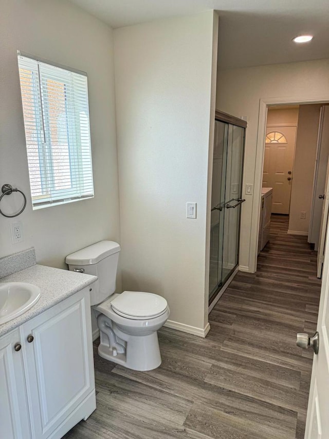 bathroom featuring vanity, hardwood / wood-style flooring, toilet, and a shower with door