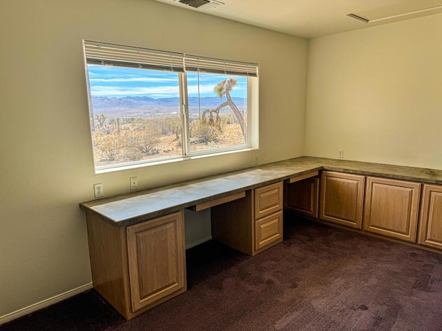 unfurnished office featuring dark colored carpet and built in desk