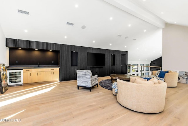 living room featuring lofted ceiling with beams, sink, beverage cooler, and light hardwood / wood-style flooring