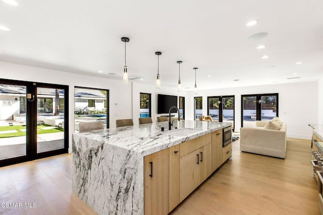 kitchen with plenty of natural light, a spacious island, light wood-type flooring, and sink