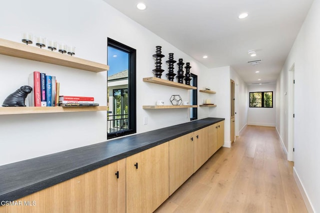 bar featuring light brown cabinets and light hardwood / wood-style floors