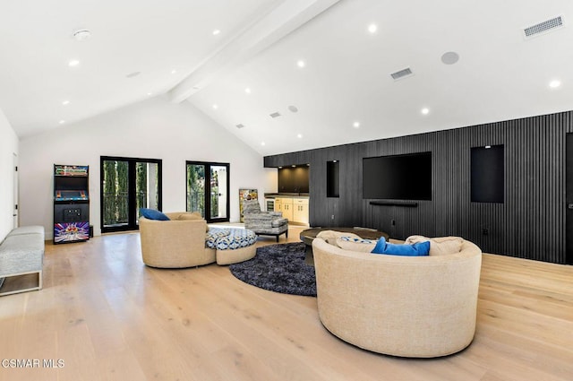 living room with beamed ceiling, high vaulted ceiling, light hardwood / wood-style flooring, and wood walls