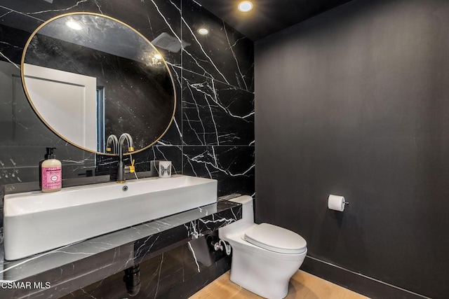 bathroom with sink, wood-type flooring, tile walls, and toilet