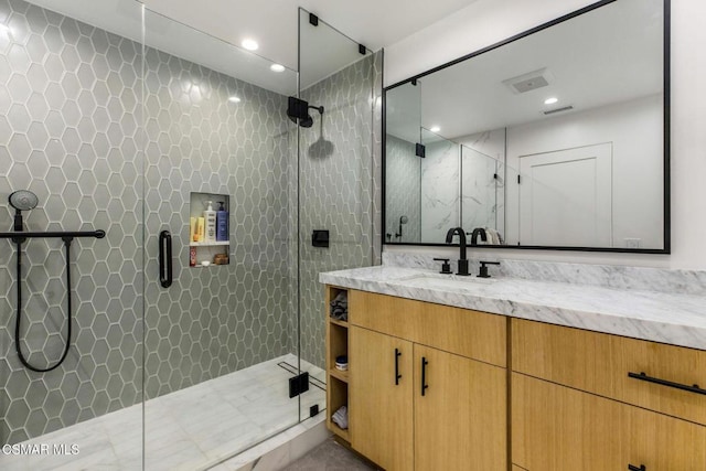 bathroom with vanity, a shower with shower door, and tile walls