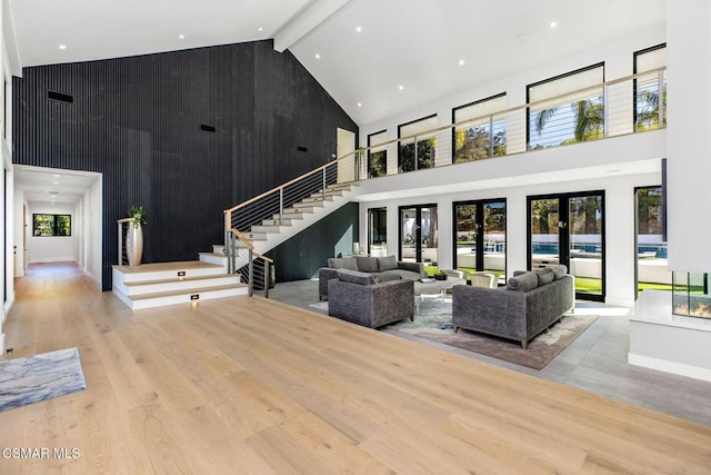 living room featuring high vaulted ceiling, french doors, wooden walls, light hardwood / wood-style flooring, and beamed ceiling