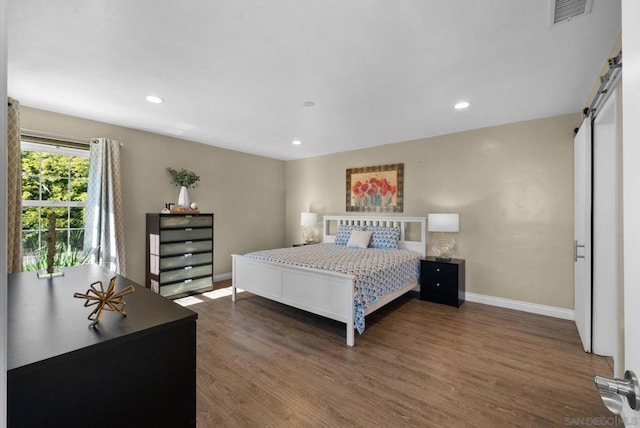 bedroom featuring dark hardwood / wood-style floors and a barn door