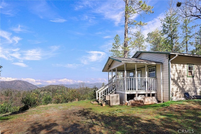 view of side of property featuring a mountain view, a porch, and cooling unit