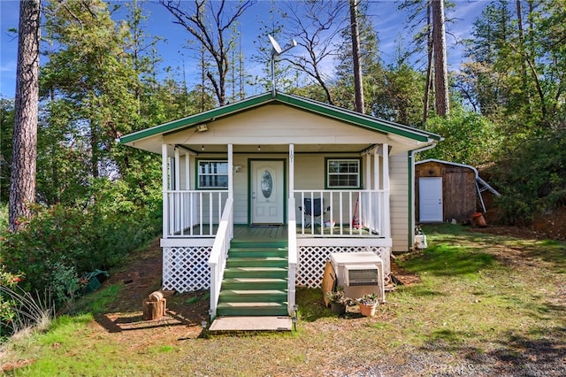 bungalow featuring a porch and a shed