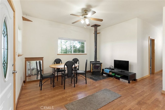 dining area featuring a wood stove, light hardwood / wood-style flooring, and ceiling fan