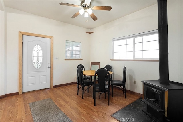 dining room with ceiling fan, light hardwood / wood-style floors, and a wood stove