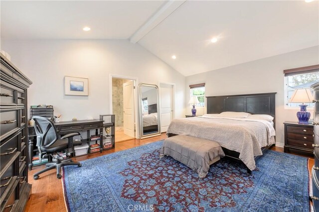 bedroom featuring wood-type flooring, vaulted ceiling with beams, and connected bathroom