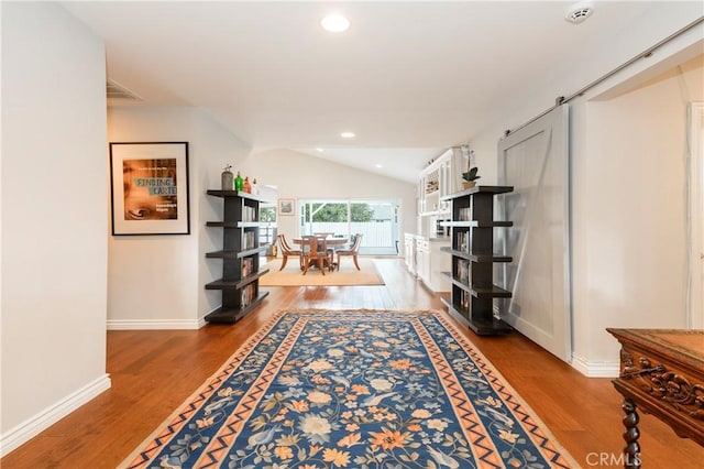 corridor with light hardwood / wood-style floors and vaulted ceiling