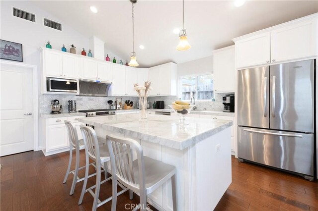 kitchen featuring dark wood-type flooring, lofted ceiling, a kitchen island with sink, white cabinets, and appliances with stainless steel finishes