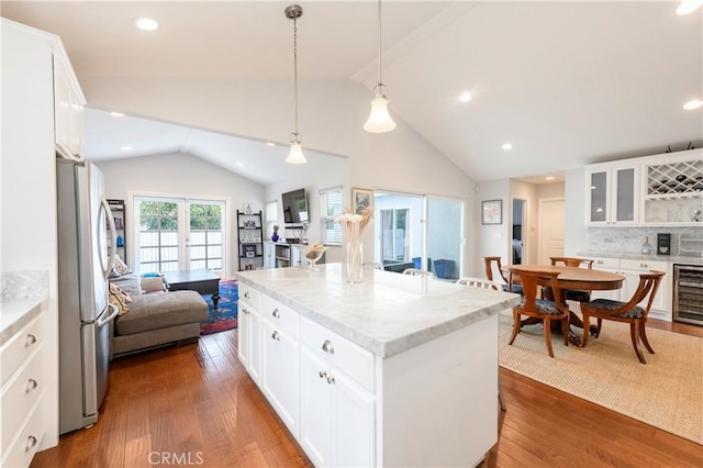 kitchen with stainless steel fridge, white cabinets, dark hardwood / wood-style floors, and a kitchen island