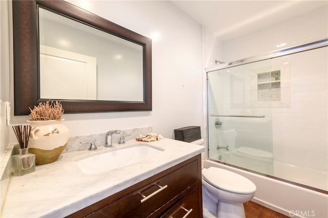 full bathroom featuring vanity, toilet, and bath / shower combo with glass door