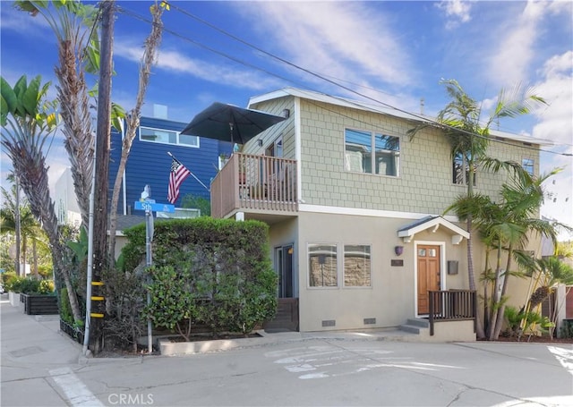 view of front of home featuring crawl space, stucco siding, and a balcony