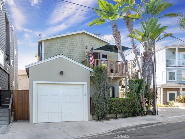 view of front of property featuring concrete driveway, a balcony, a garage, and stucco siding