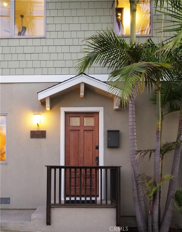 entrance to property featuring visible vents and stucco siding