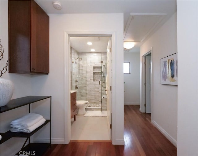 hall featuring attic access, baseboards, and wood finished floors