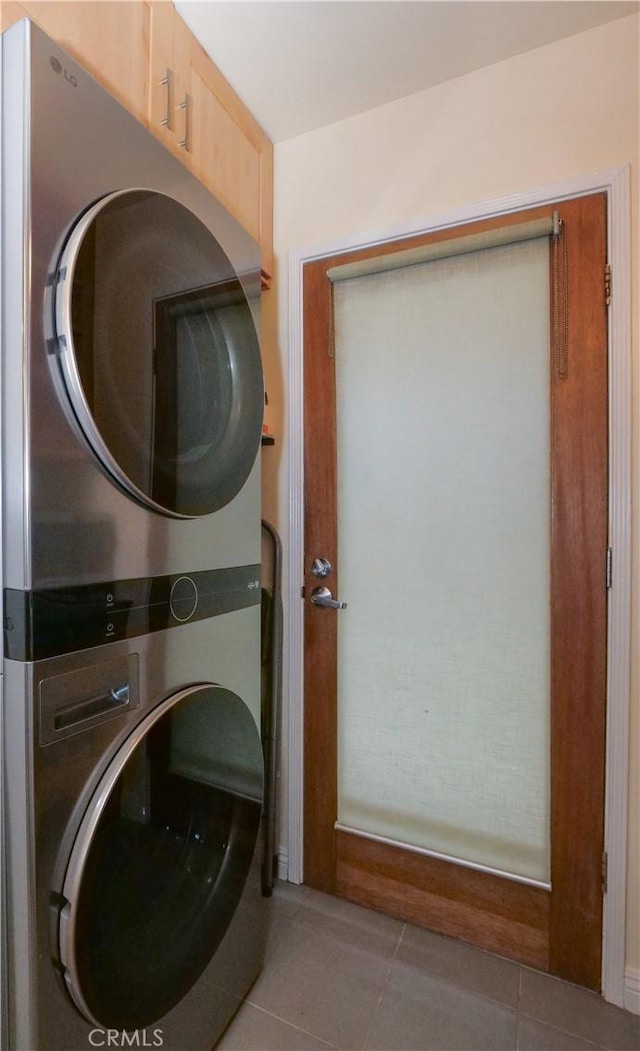 clothes washing area with tile patterned floors, stacked washer and clothes dryer, and laundry area