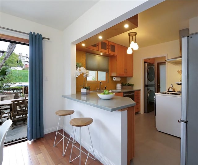 kitchen featuring glass insert cabinets, recessed lighting, a kitchen breakfast bar, a peninsula, and freestanding refrigerator