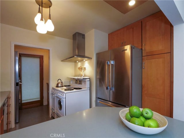 kitchen featuring electric range, brown cabinets, high end fridge, wall chimney range hood, and light countertops