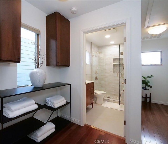 bathroom with visible vents, a stall shower, wood finished floors, baseboards, and vanity