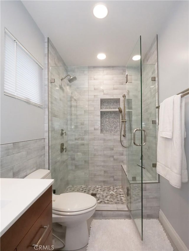 bathroom with toilet, a stall shower, and vanity