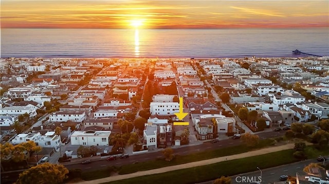 aerial view at dusk featuring a residential view and a water view