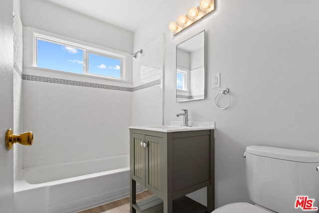 full bathroom with hardwood / wood-style floors, vanity, toilet, and tiled shower / bath