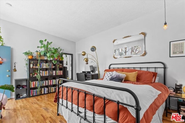 bedroom with a textured ceiling and light hardwood / wood-style floors