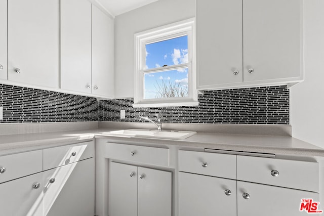 kitchen with decorative backsplash, white cabinetry, and sink