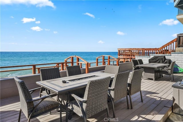 wooden terrace featuring a fire pit and a water view