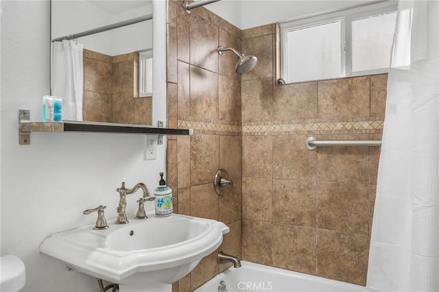 bathroom featuring shower / bath combination with curtain, a healthy amount of sunlight, and sink